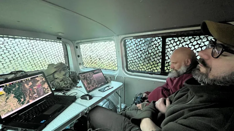 Antžeminė stotis mikroautobuse: monitoriai, kompiuteris ir du operatoriai