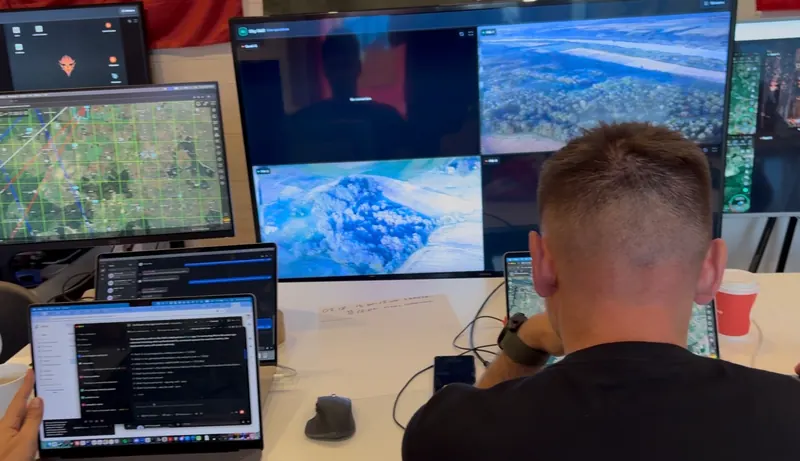 Operatoriai prie kelių monitorių su žemėlapiais ir vaizdais iš oro