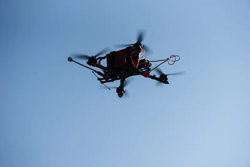 FPV dronas skrydyje giedro mėlyno dangaus fone