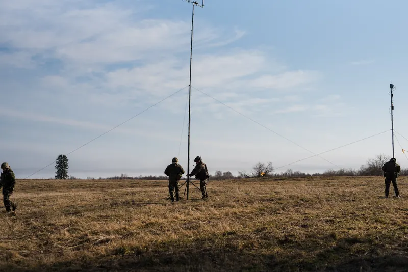 Du antenų stiebai ir šauliai lauke sutemus