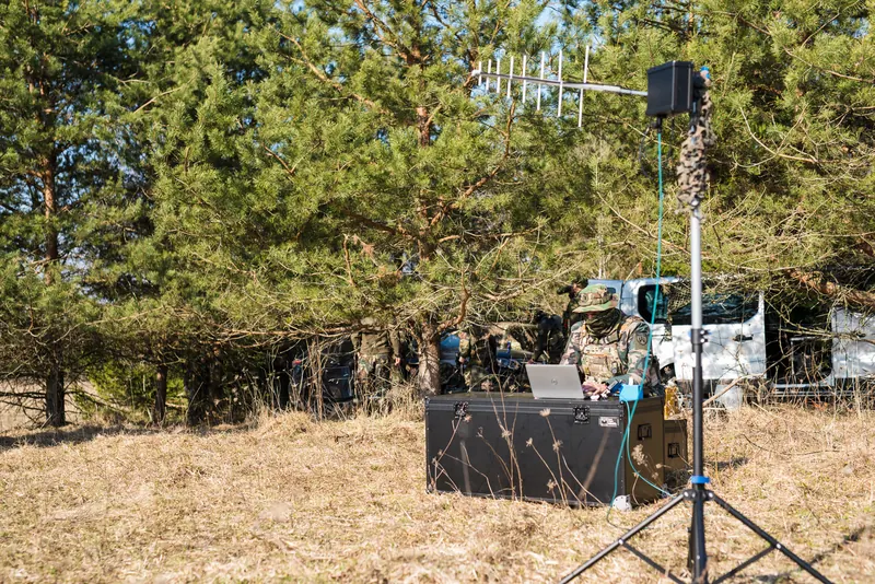 Yagi antenos stiebas ir antžeminė stotis ant transportavimo dėžės, operatorius su šaliku