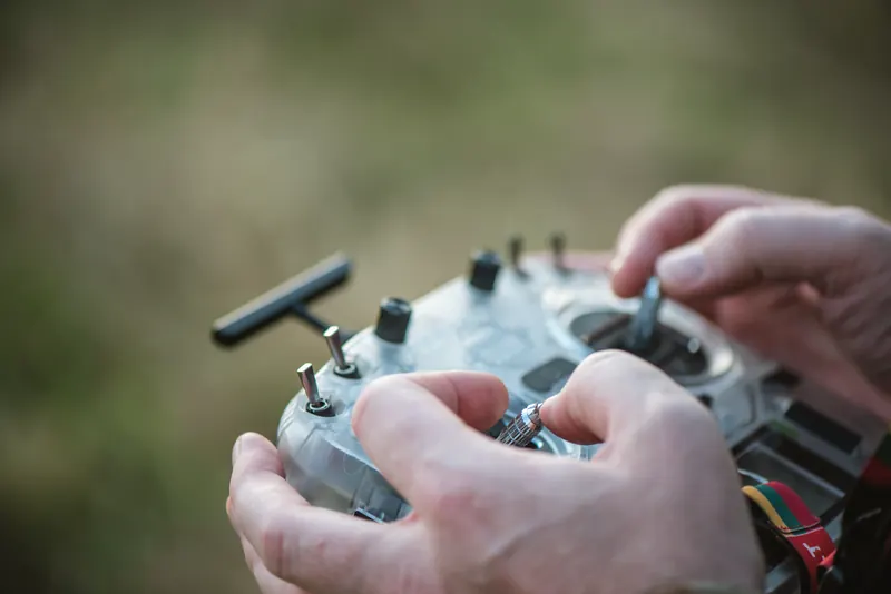 Rankos ant skaidraus RadioMaster pulto, fone žalia žolė