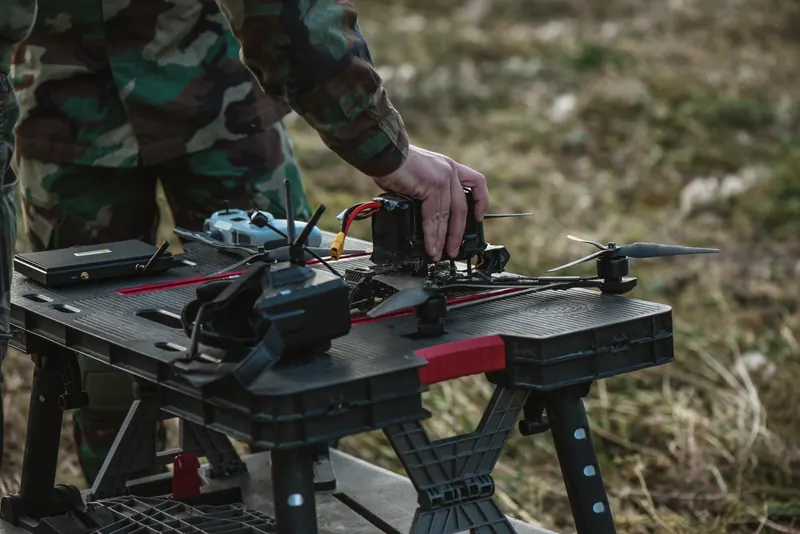 Rankos surenka FPV droną ant juodo nešiojamo darbastalio lauke